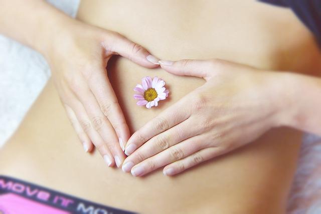 a woman holding her hands on her belly, with a daisy in her belly button