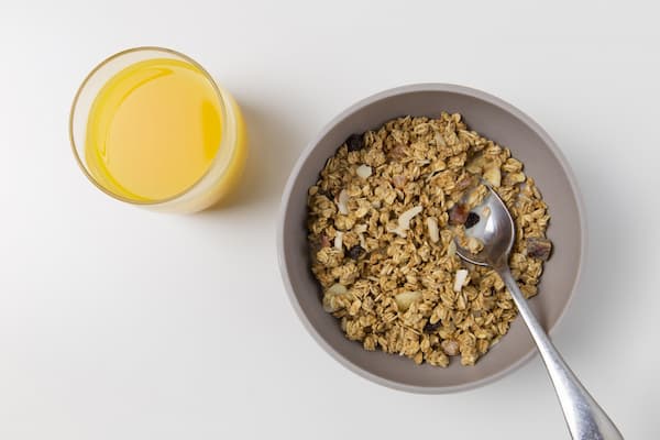 A glass of orange juice next to a bowl of oatmeal. 